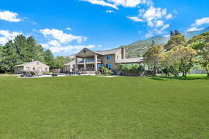 Back of property with a mountain view, a patio, a lawn, and an outdoor pool