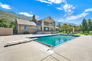 View of swimming pool with a mountain view, a patio, a diving board, and a covered pool