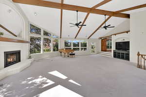 Unfurnished living room with beamed ceiling, high vaulted ceiling, carpet flooring, a fireplace, and billiards table