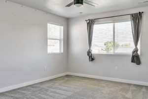 Carpeted empty room featuring baseboards and a ceiling fan