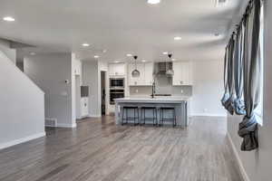 Kitchen featuring tasteful backsplash, light countertops, white cabinetry, wood finished floors, and stainless steel appliances