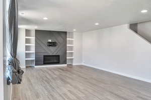Unfurnished living room with light wood finished floors, recessed lighting, and a fireplace
