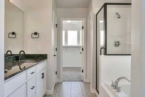 Bathroom featuring a stall shower, vanity, tile patterned flooring, and a garden tub