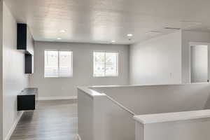 Corridor featuring an upstairs landing, wood finished floors, and recessed lighting
