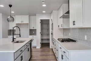 Kitchen with wood finished floors, light stone countertops, recessed lighting, decorative light fixtures, and white cabinets