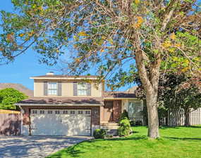 Split level home with a garage, driveway, brick siding, and a chimney