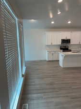 Kitchen featuring white cabinets, appliances with stainless steel finishes, recessed lighting, dark wood-style floors, and a breakfast bar area