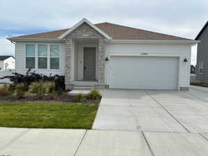 Single story home with stone siding, driveway, a garage, and a shingled roof