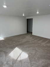 Carpeted spare room featuring a textured ceiling and recessed lighting