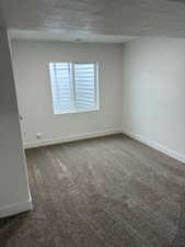 Empty room featuring dark colored carpet and baseboards