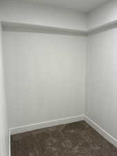Empty room featuring dark colored carpet and baseboards