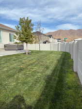 Fenced backyard with a mountain view, a hot tub, and a patio area