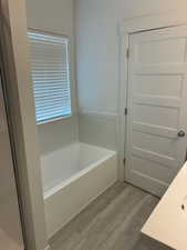 Bathroom with a bath, vanity, and light wood-style flooring