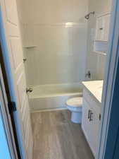 Bathroom with vanity, shower / bath combination, and dark wood-style flooring