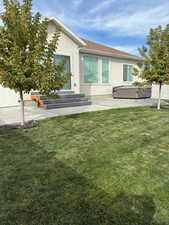 Back of house featuring stucco siding, a patio area, a hot tub, and a shingled roof