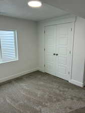 Unfurnished bedroom featuring carpet, a closet, and a textured ceiling