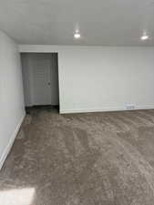 Spare room with dark carpet and a textured ceiling