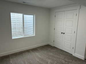 Unfurnished bedroom featuring dark carpet and a closet