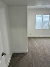 Unfurnished room with dark carpet and baseboards