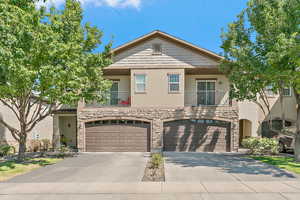 View of front facade featuring stone siding, a garage, stucco siding, and driveway