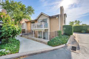 View of front of property with brick siding, a chimney, and a balcony