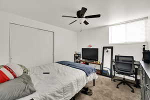 Bedroom with carpet flooring, an office area, and ceiling fan