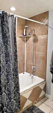 Full bathroom featuring tiled shower / bath, a textured ceiling, and tile patterned floors