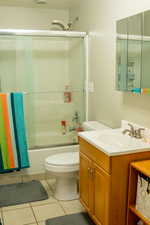 Bathroom featuring vanity, tile patterned flooring, and combined bath / shower with glass door