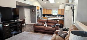 Living area with recessed lighting, dark wood finished floors, vaulted ceiling, and a skylight