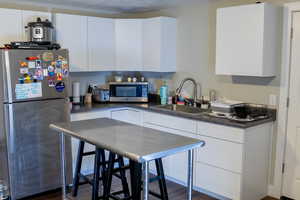 Kitchen with stainless steel appliances, white cabinets, dark countertops, and a textured ceiling