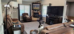 Living room with healthy amount of natural light, vaulted ceiling, wood finished floors, and a stone fireplace