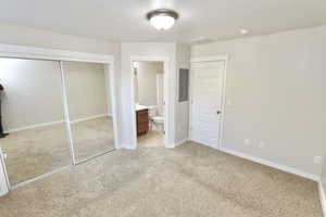 Second bedroom with light colored carpet,  a large closet, and en suite bathroom