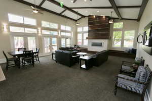 Living area featuring dark colored carpet, a large fireplace, beam ceiling, high vaulted ceiling, and french doors