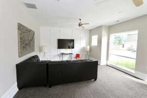 Carpeted living area featuring baseboards and ceiling fan