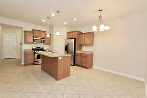 Dining room & Kitchen with stainless steel appliances, light countertops, a kitchen island with sink, a large walk-in pantry and recessed lighting. Light tile floors.
