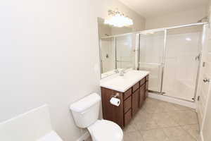 Primary bathroom shower, vanity, and tile floors