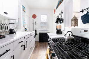 Kitchen featuring gas stove, light wood-style flooring, light countertops, and white cabinets