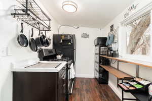 Kitchen with gas stove, dark wood-type flooring, light countertops, dark brown cabinets, and freestanding refrigerator
