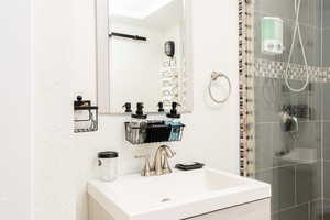 Bathroom with a stall shower, a textured wall, and vanity