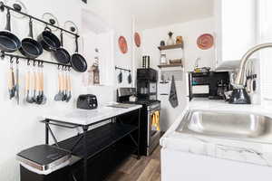 Kitchen featuring stainless steel gas range, wood finished floors, and open shelves