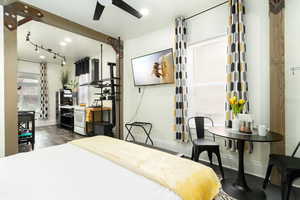 Bedroom with dark wood-style floors, track lighting, and a ceiling fan