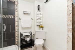 Full bathroom with a stall shower, tile patterned flooring, and a textured wall