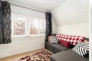Living area with carpet floors, wooden walls, and lofted ceiling