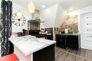 Kitchen with tile walls, black appliances, dark cabinetry, dark wood finished floors, and ventilation hood