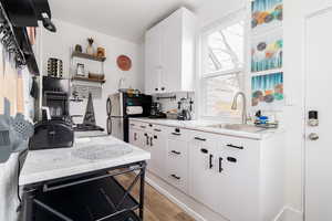 Kitchen with light wood-style flooring, freestanding refrigerator, and white cabinetry