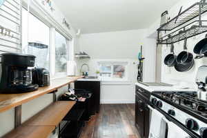 Kitchen with dark cabinetry, dark wood-type flooring, wood counters, and stainless steel gas range oven