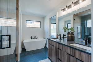 Full bath with double vanity, a freestanding bath, tile patterned flooring, and a shower stall