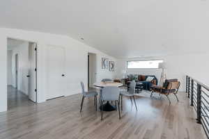 Dining area with light wood-style flooring and vaulted ceiling