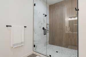 Bathroom with a shower stall and baseboards