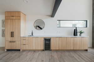Bar area with wine cooler and light wood-style floors